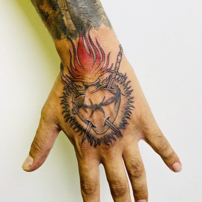 Tatuaje de un corazón en llamas en la mano