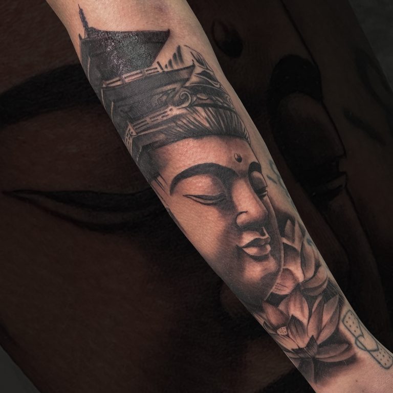 Tatuaje realista de un buda en el antebrazo
